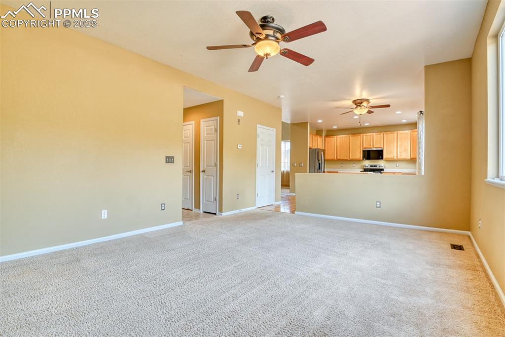 Image 22 of 49: Unfurnished living room featuring light colored carpet, a ceiling fan, and