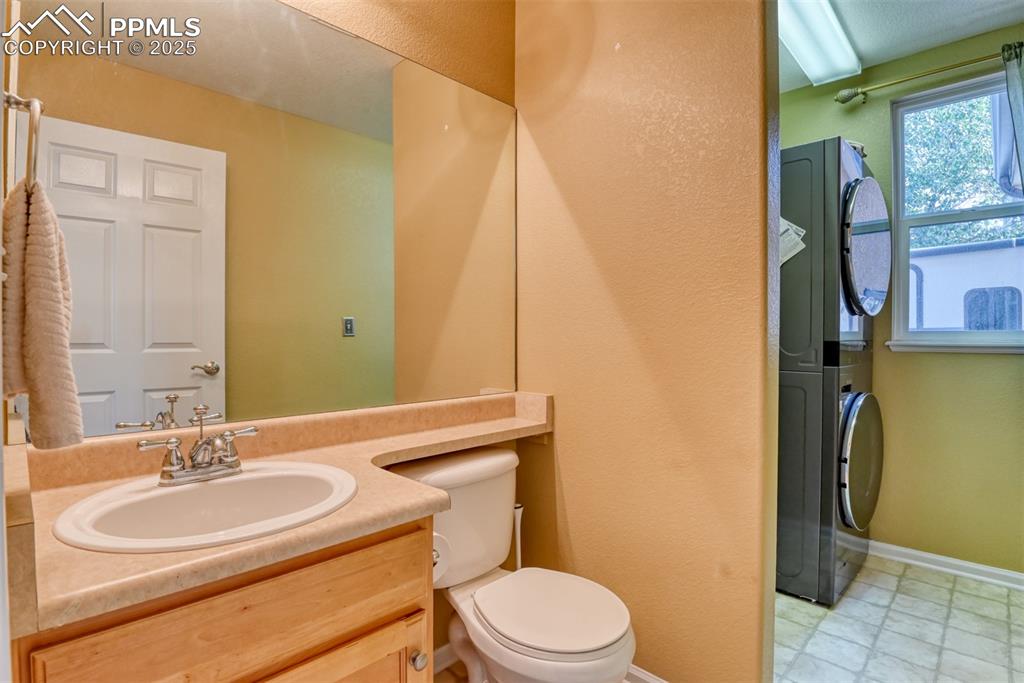 Image 23 of 49: Bathroom with vanity, stacked washer / drying machine, and a textured wall