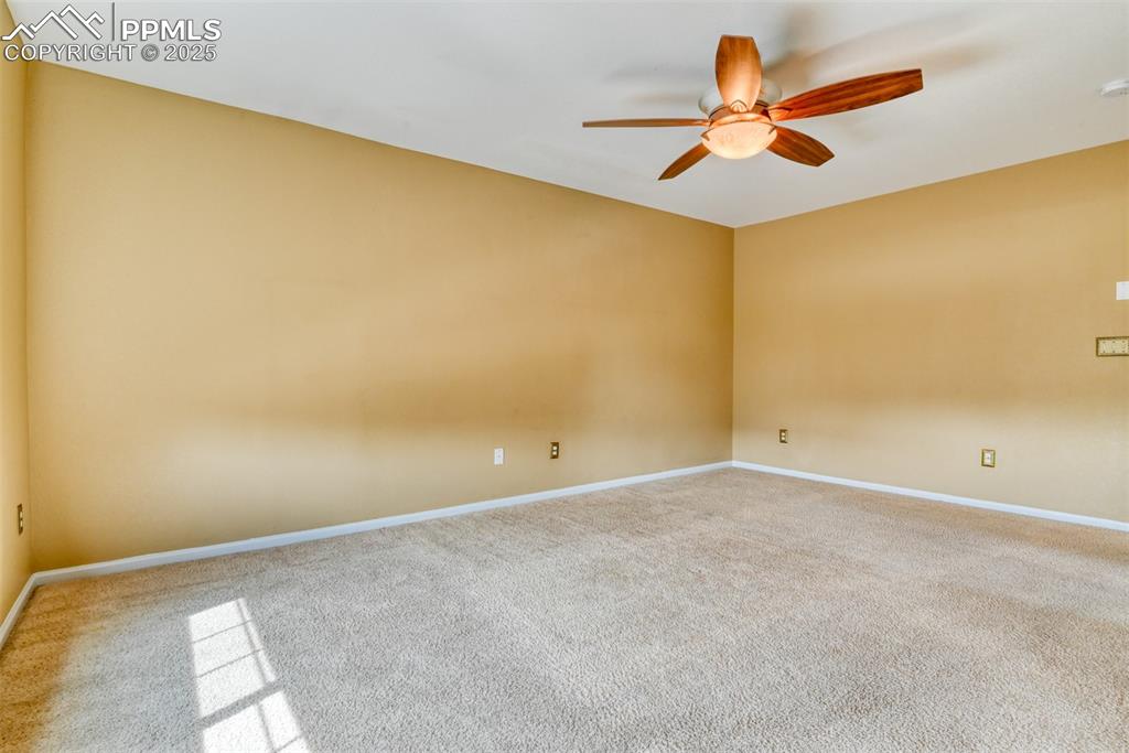 Image 27 of 49: Carpeted spare room with baseboards and ceiling fan
