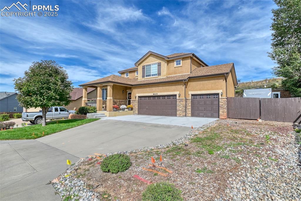 Image 4 of 49: View of front facade featuring stucco siding, driveway, and stone siding