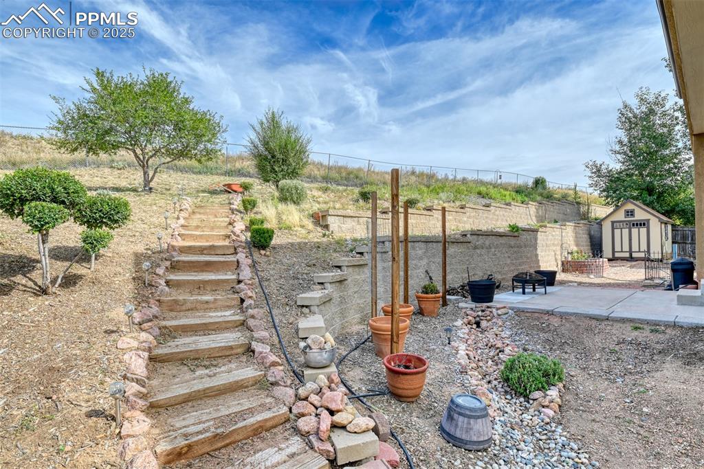 Image 46 of 49: View of yard with a shed, a patio, an outdoor fire pit, and stairway