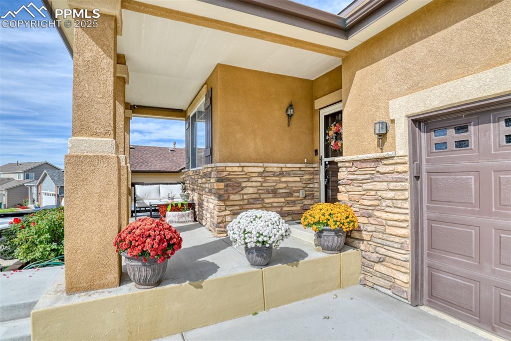Image 5 of 49: Property entrance with stone siding, stucco siding, and a porch