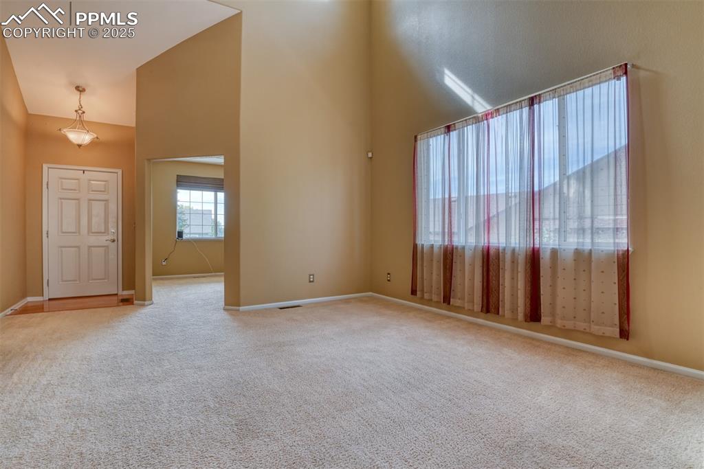 Image 6 of 49: Empty room with a high ceiling and light carpet