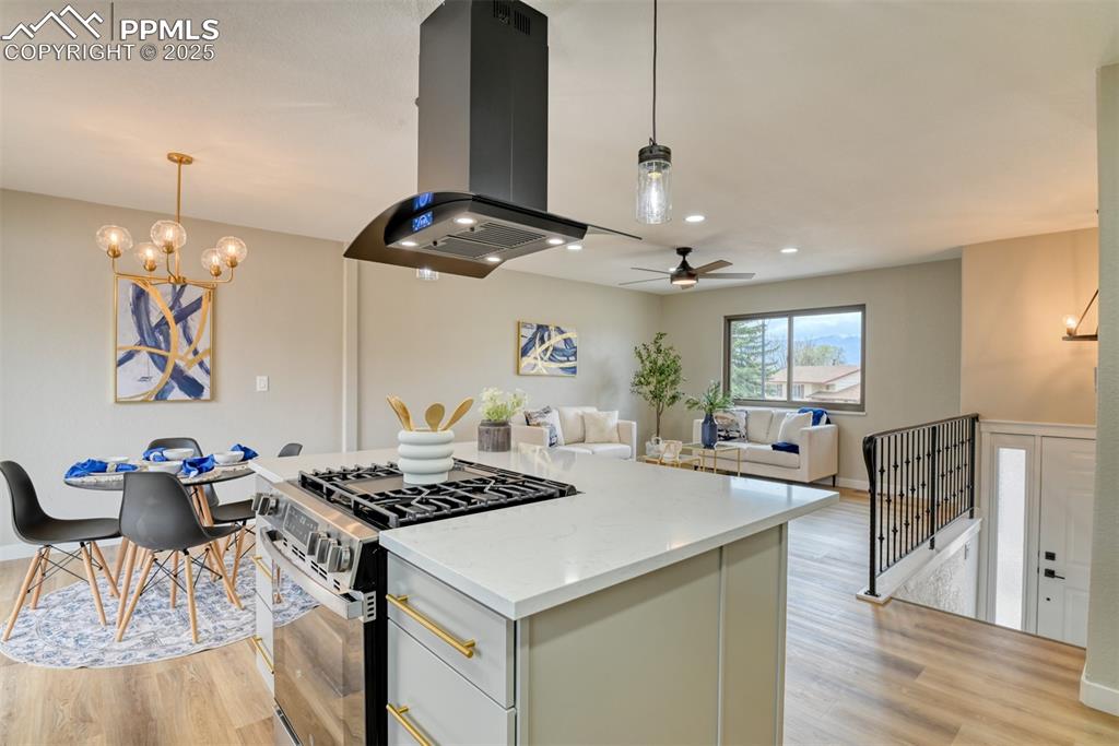 Image 15 of 45: Kitchen with stainless steel gas range, light wood-style floors, island ran