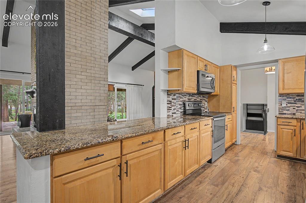 Image 11 of 46: Kitchen featuring light wood cabinetry, stone countertops, stainless steel