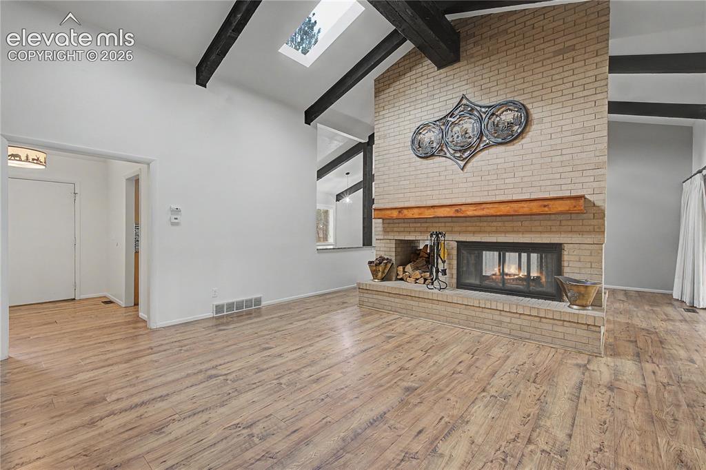 Image 13 of 46: Expansive living area featuring a floor-to-ceiling brick fireplace with a w