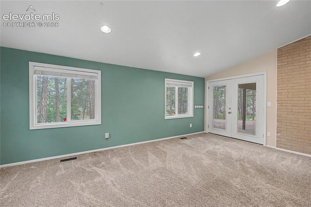 Image 16 of 46: Spacious room featuring neutral carpet flooring, two windows with white tri