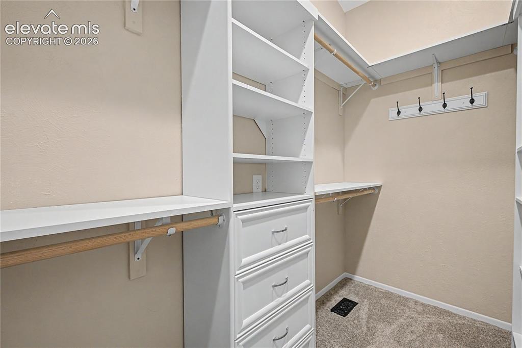 Image 21 of 46: Walk-in closet featuring built-in white shelving, integrated drawers, multi