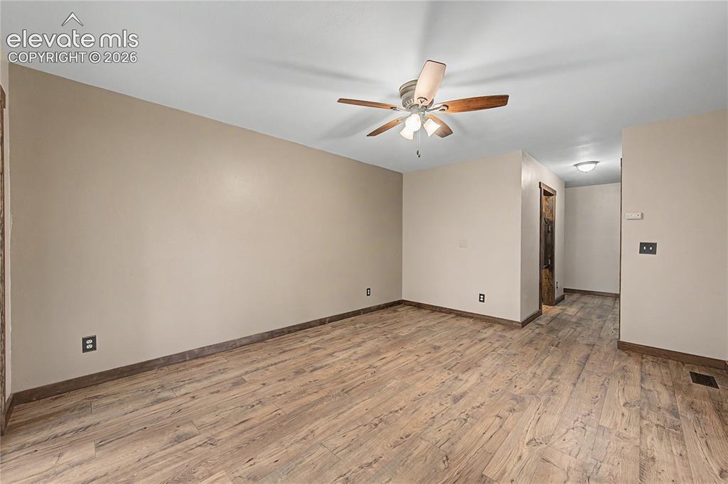 Image 23 of 46: Spacious room featuring wood-finish flooring, neutral-toned walls, and a ce