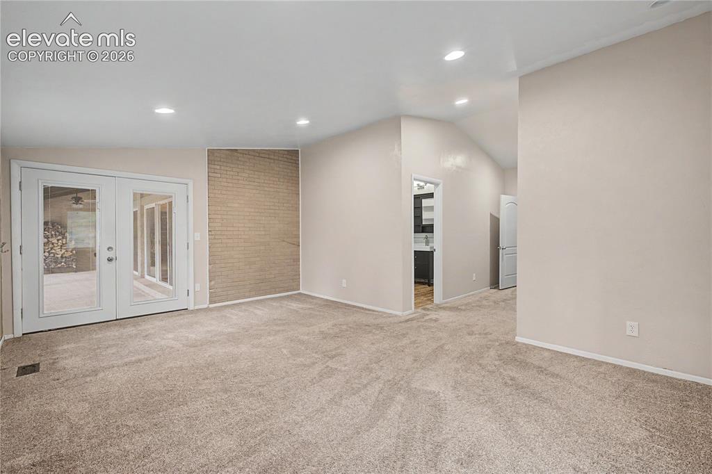 Image 25 of 46: Carpeted interior space featuring a light brick accent wall, recessed light