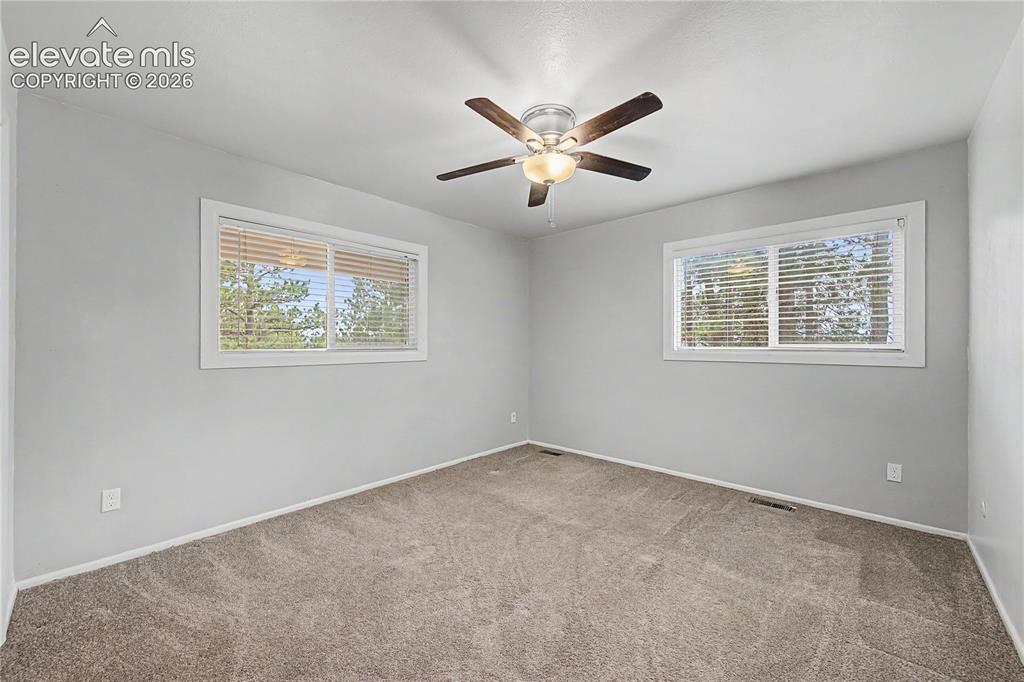 Image 28 of 46: Spacious room featuring neutral carpeting, light gray wall finishes, and tw