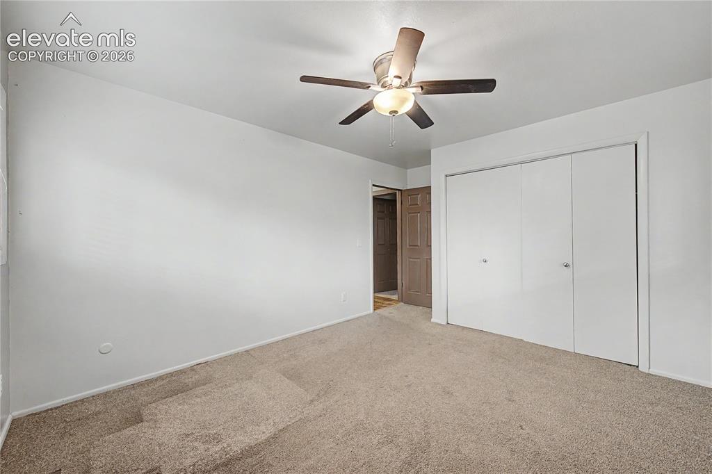Image 29 of 46: Carpeted interior space featuring a ceiling fan with light fixture, bi-fold