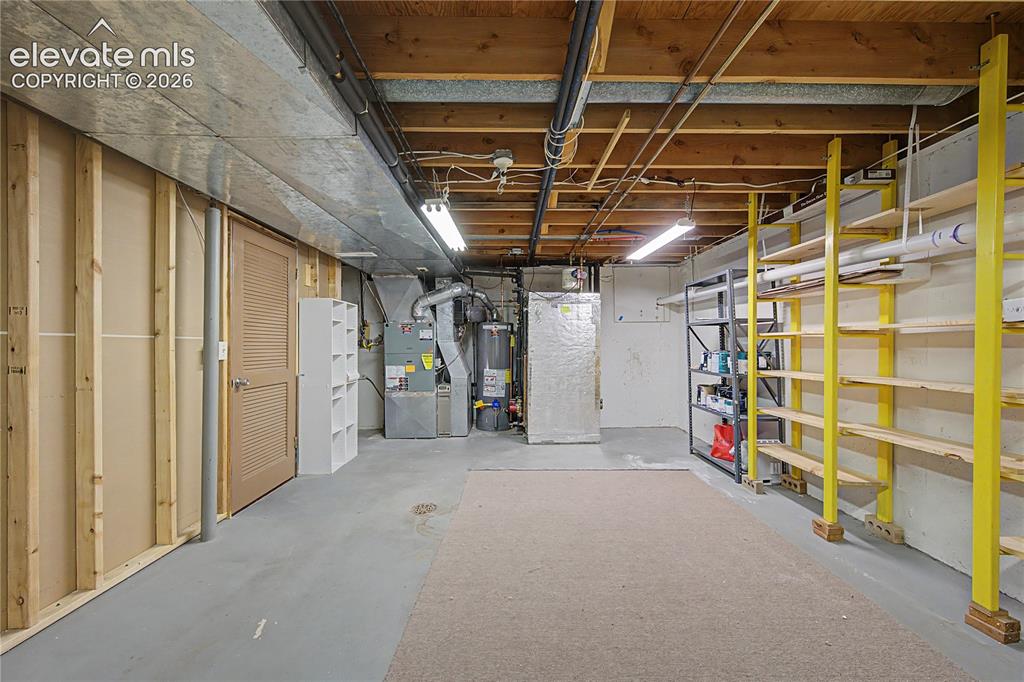 Image 37 of 46: Unfinished basement space featuring exposed wooden ceiling joists, concrete