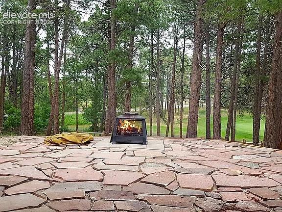 Image 6 of 46: Expansive natural stone patio featuring a freestanding fire pit