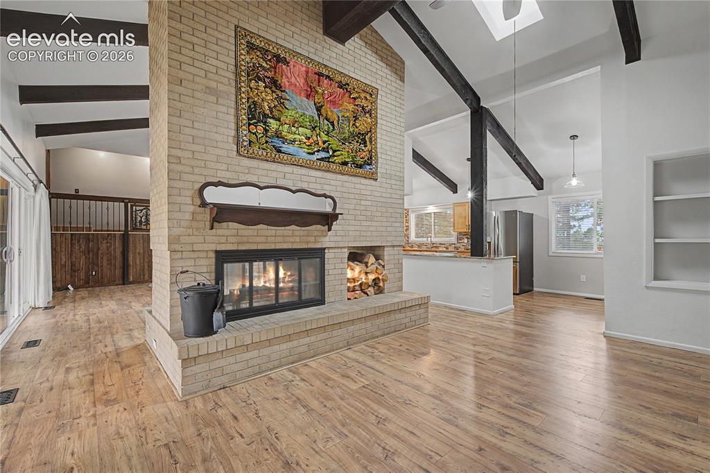 Image 8 of 46: Central brick fireplace with a wood mantel and hearth