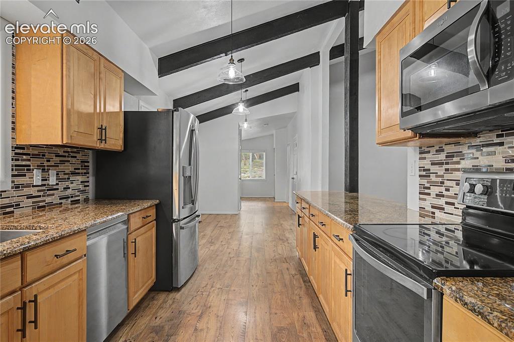 Image 9 of 46: Kitchen featuring wood-finish flooring, natural wood cabinetry, and granite