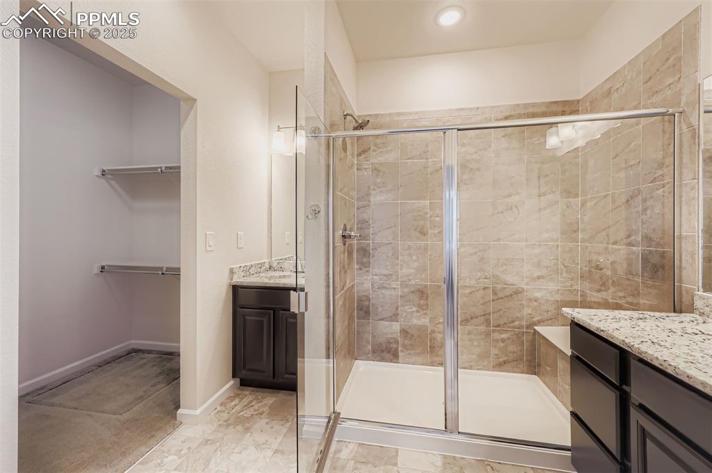Image 17 of 30: Bathroom with vanity, a shower stall, and a walk in closet