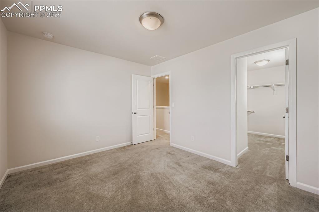 Image 20 of 30: Unfurnished bedroom with a spacious closet and light colored carpet