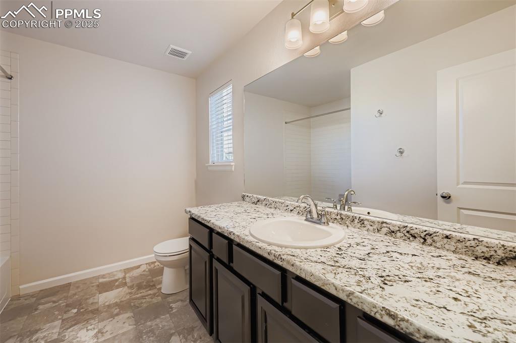 Image 23 of 30: Bathroom with vanity, light stone finish floors, and  shower combination