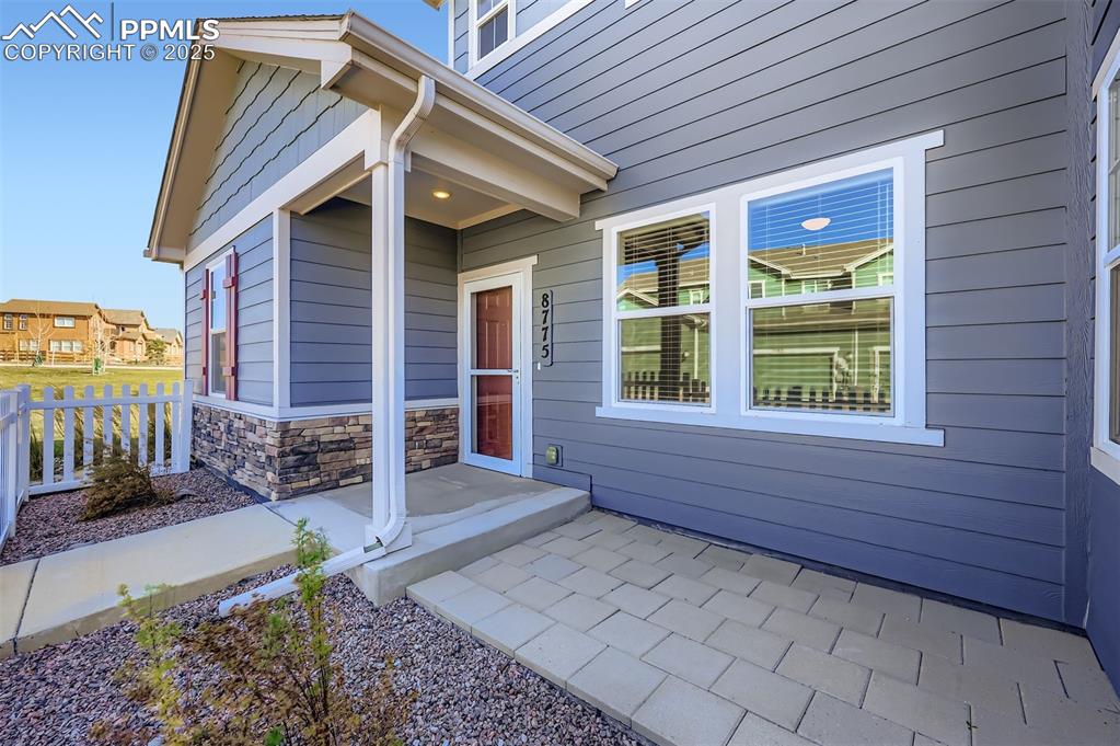 Image 27 of 30: View of exterior entry featuring covered porch and stone siding