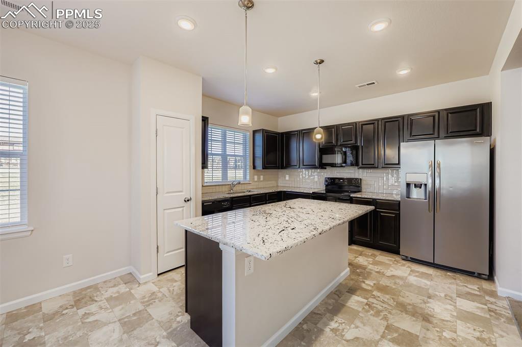 Image 8 of 30: Kitchen with black appliances, tasteful backsplash, a kitchen island, decor