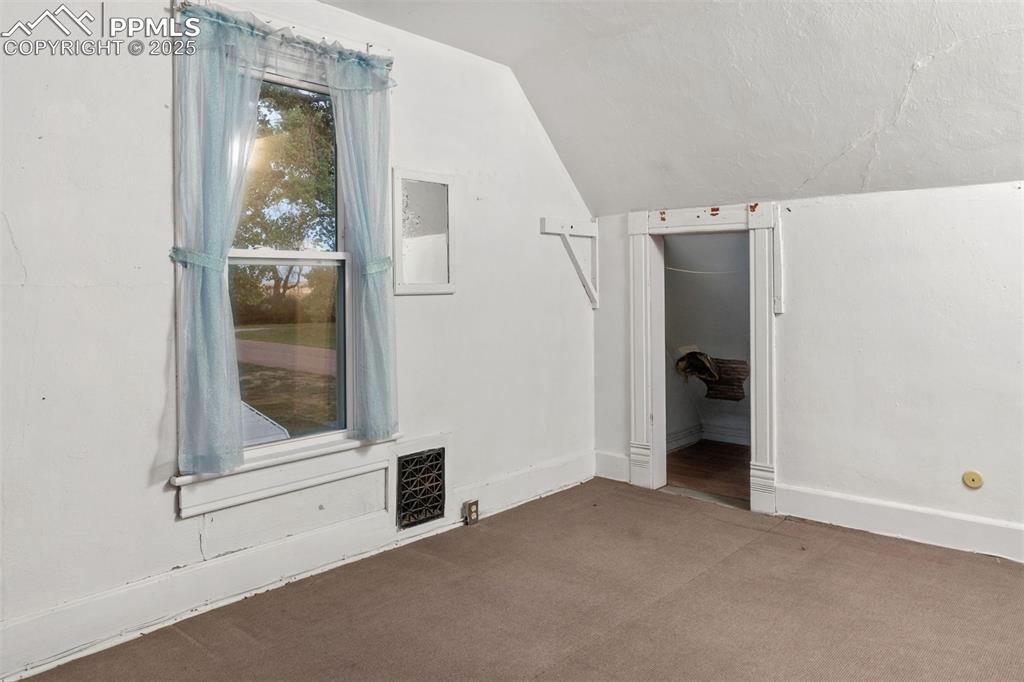 Image 17 of 24: Additional living space with vaulted ceiling and carpet