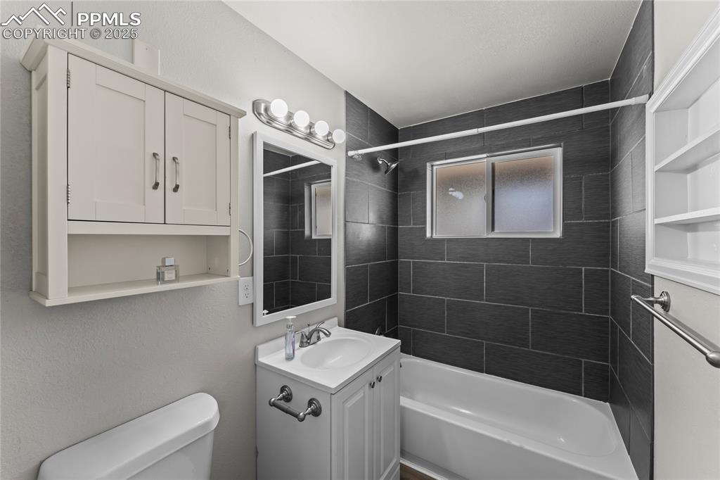 Image 15 of 24: Bathroom featuring shower / washtub combination, vanity, and a textured wal