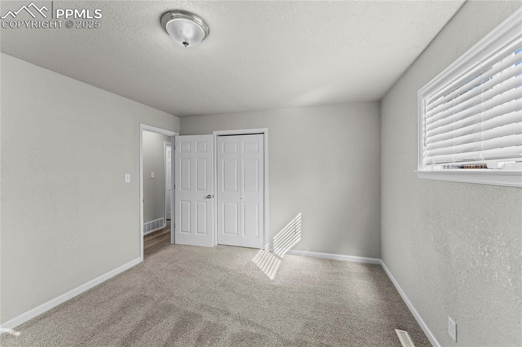 Image 17 of 24: Unfurnished bedroom featuring carpet floors, a textured ceiling, a closet,