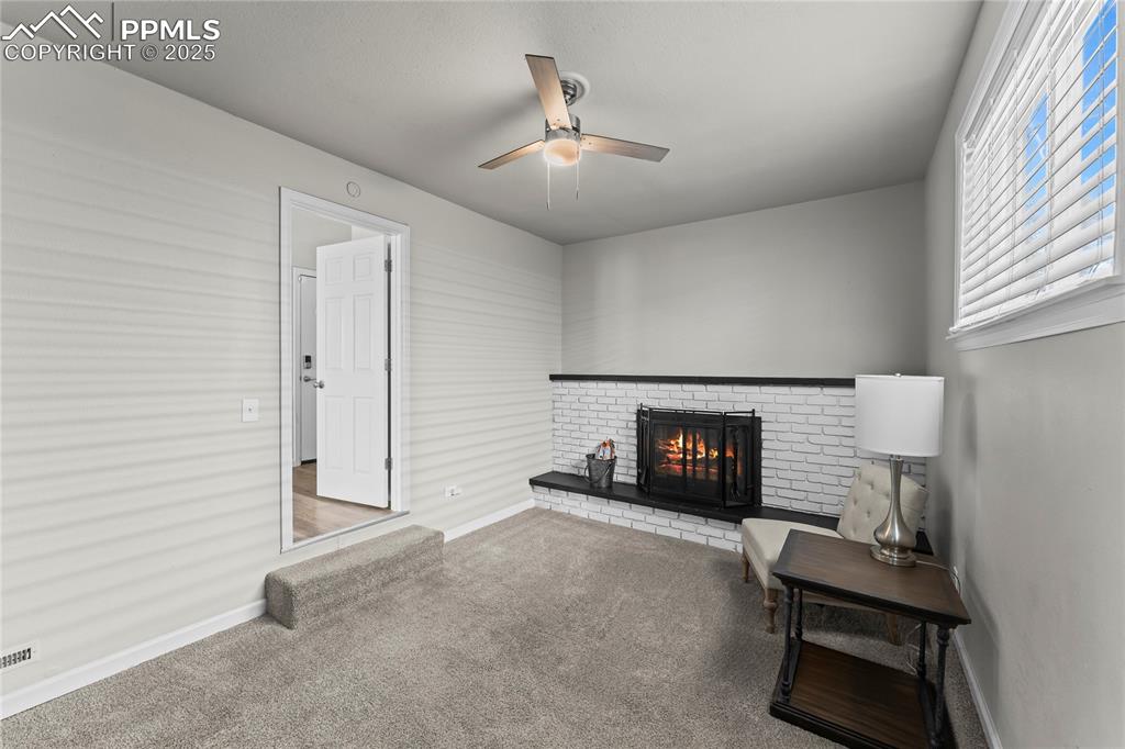 Image 5 of 24: Sitting room featuring a brick fireplace, carpet, and ceiling fan