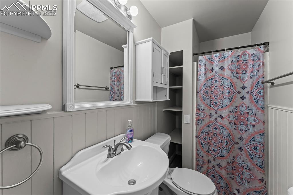 Image 8 of 24: Bathroom featuring a shower with shower curtain and a wainscoted wall