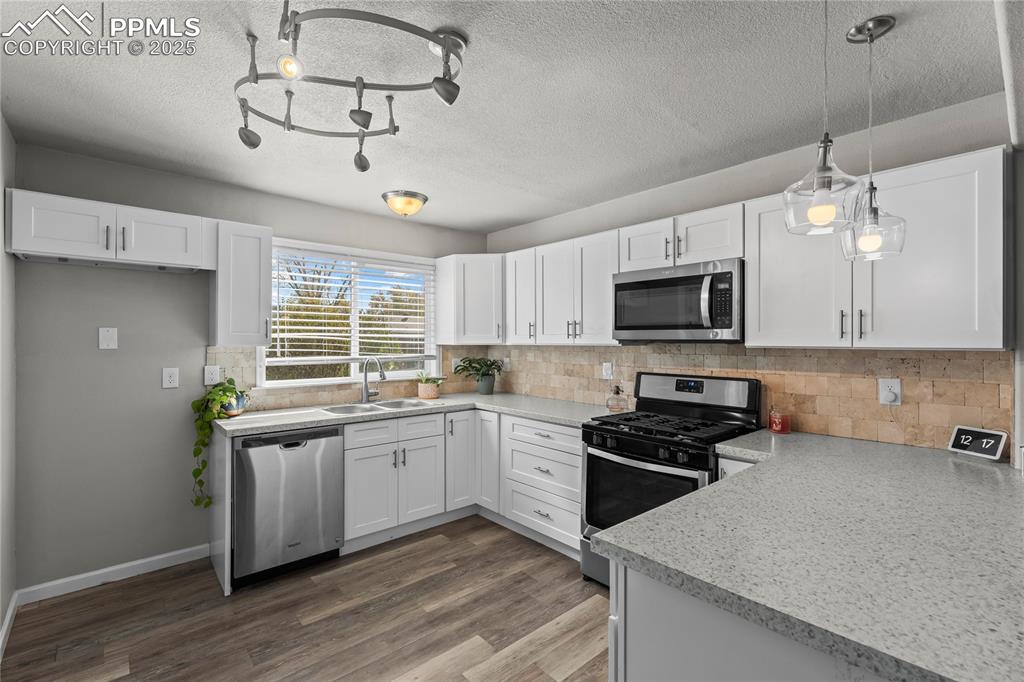 Image 9 of 24: Kitchen with stainless steel appliances, white cabinets, light countertops,