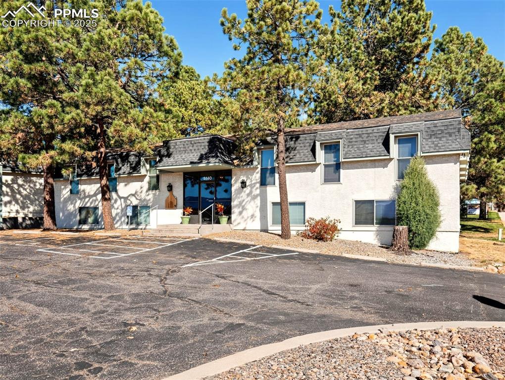 Image 1 of 17: View of property featuring uncovered parking and view of wooded area