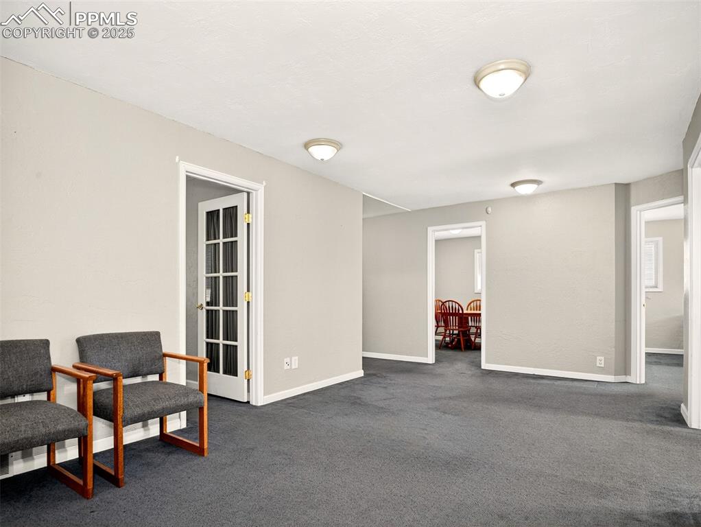 Image 11 of 17: Sitting room with dark carpet and baseboards