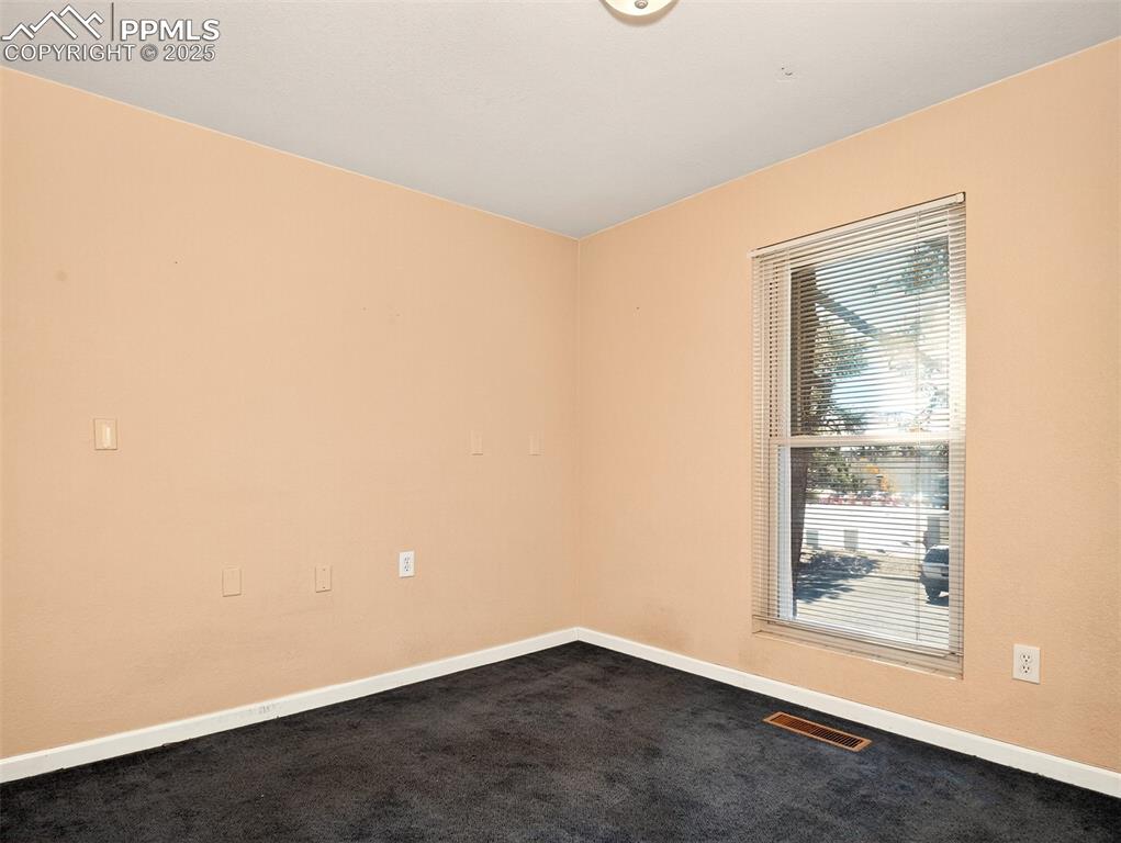 Image 13 of 17: Empty room featuring dark colored carpet and baseboards