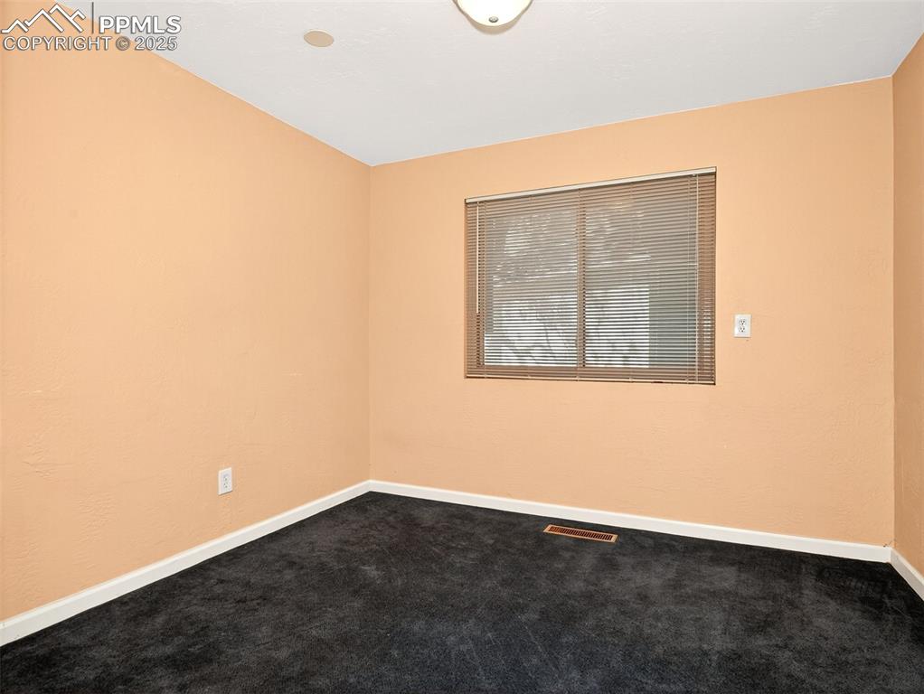 Image 15 of 17: Empty room with dark carpet and baseboards
