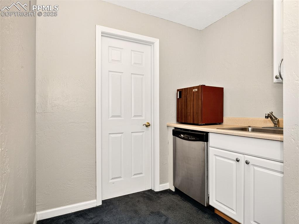 Image 17 of 17: Kitchen featuring a textured wall, white cabinetry, light countertops, dish