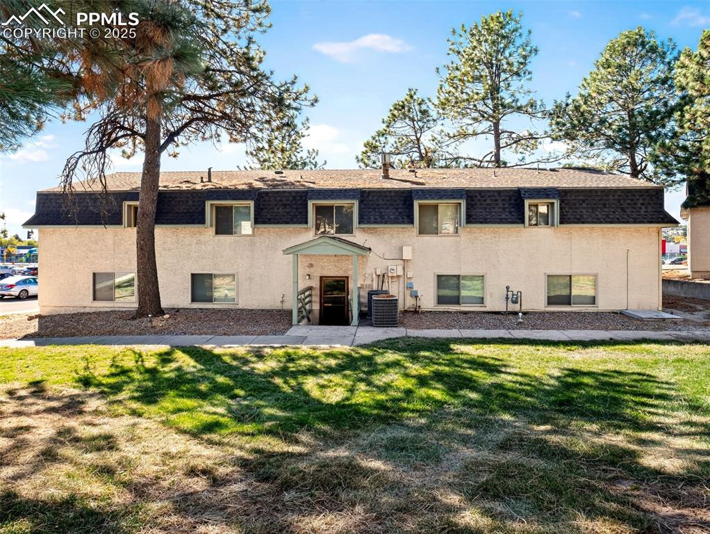 Image 3 of 17: Back of house with a shingled roof, a yard, mansard roof, and stucco siding