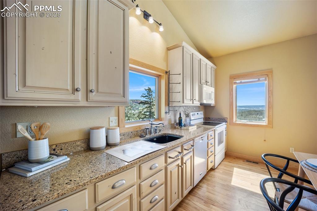 Image 12 of 50: Kitchen featuring white appliances, lofted ceiling, light wood-style floori