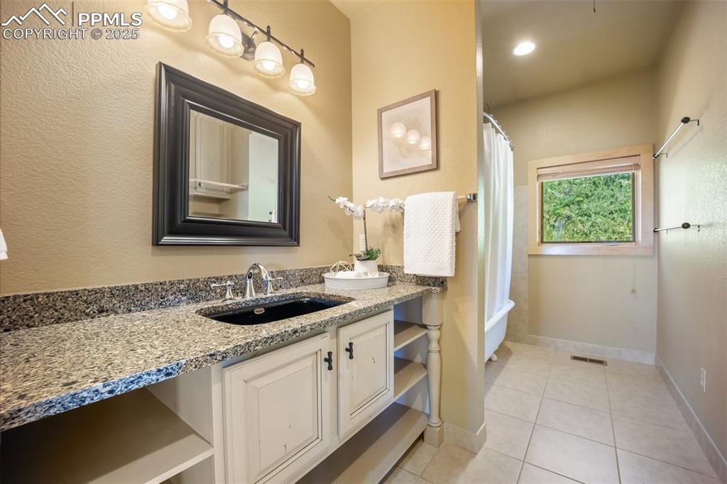 Image 23 of 50: Full bath featuring double vanity, tile patterned flooring, and shower / ba