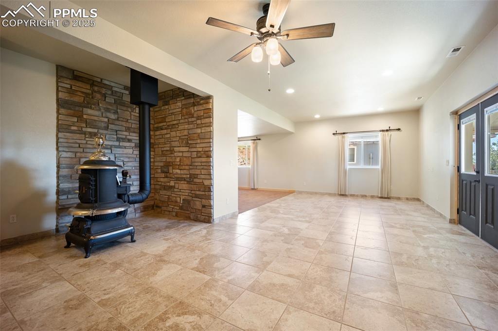 Image 26 of 50: Unfurnished living room featuring a wood stove, ceiling fan, and recessed l