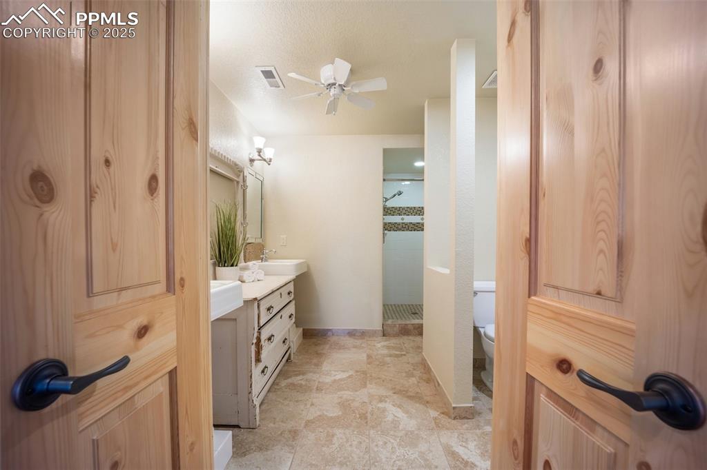 Image 32 of 50: Bathroom featuring a shower stall, vanity, and ceiling fan