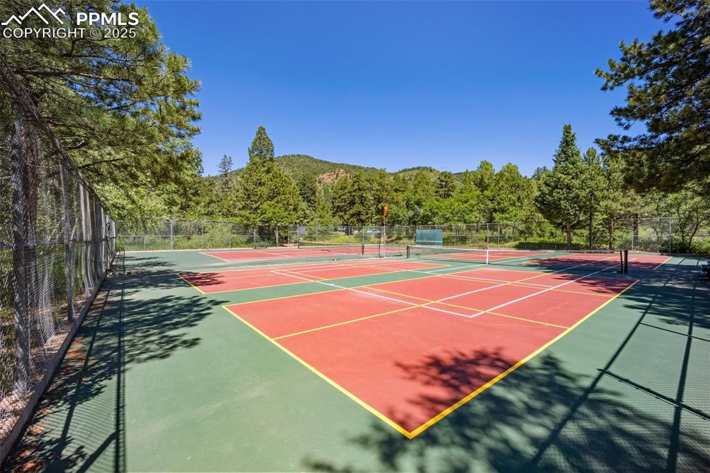 Image 48 of 50: View of tennis court featuring community basketball court and a view of tre