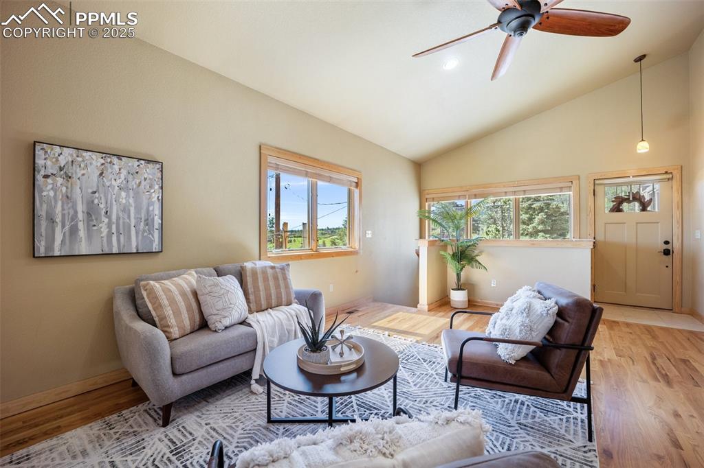 Image 6 of 50: Living room with wood finished floors, a ceiling fan, and vaulted ceiling