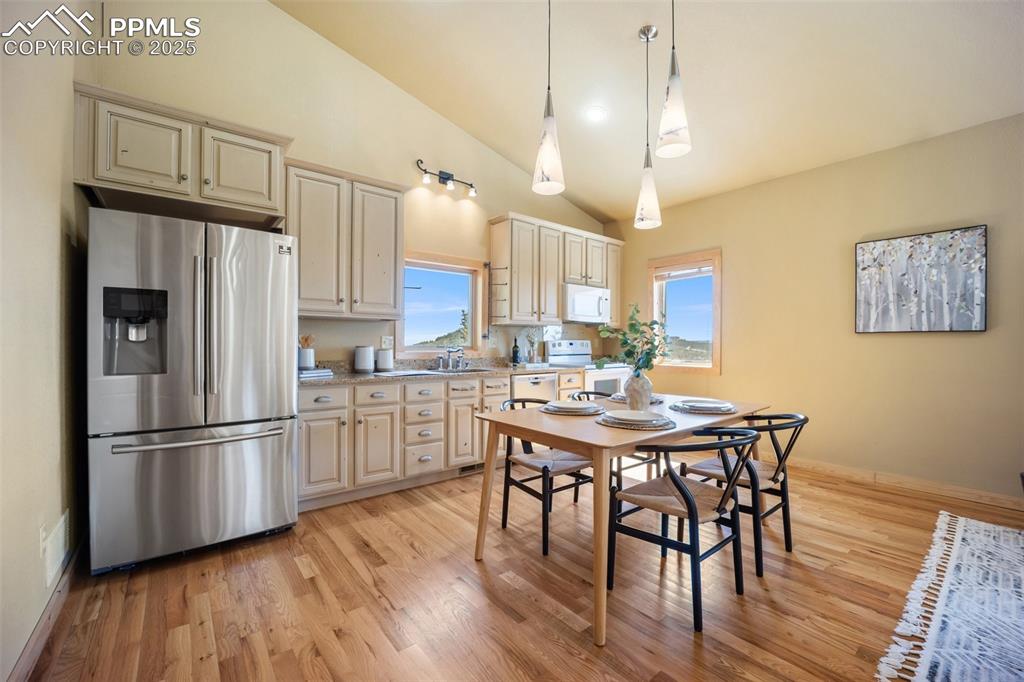 Image 9 of 50: Kitchen featuring white appliances, light countertops, light wood-style flo