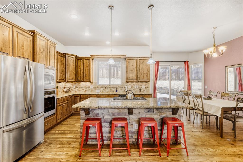 Image 12 of 47: Kitchen with stainless steel appliances, a kitchen island, tiled backsplash