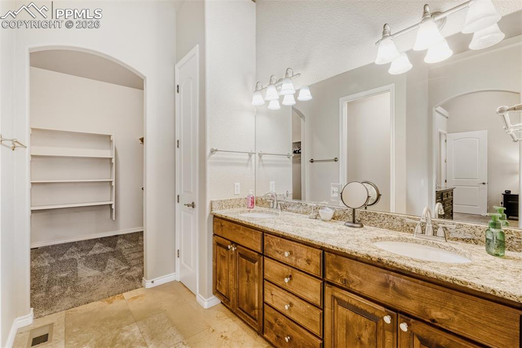 Image 21 of 47: 5-piece bathroom with double vanity, a walk-in closet, and Travertine floor