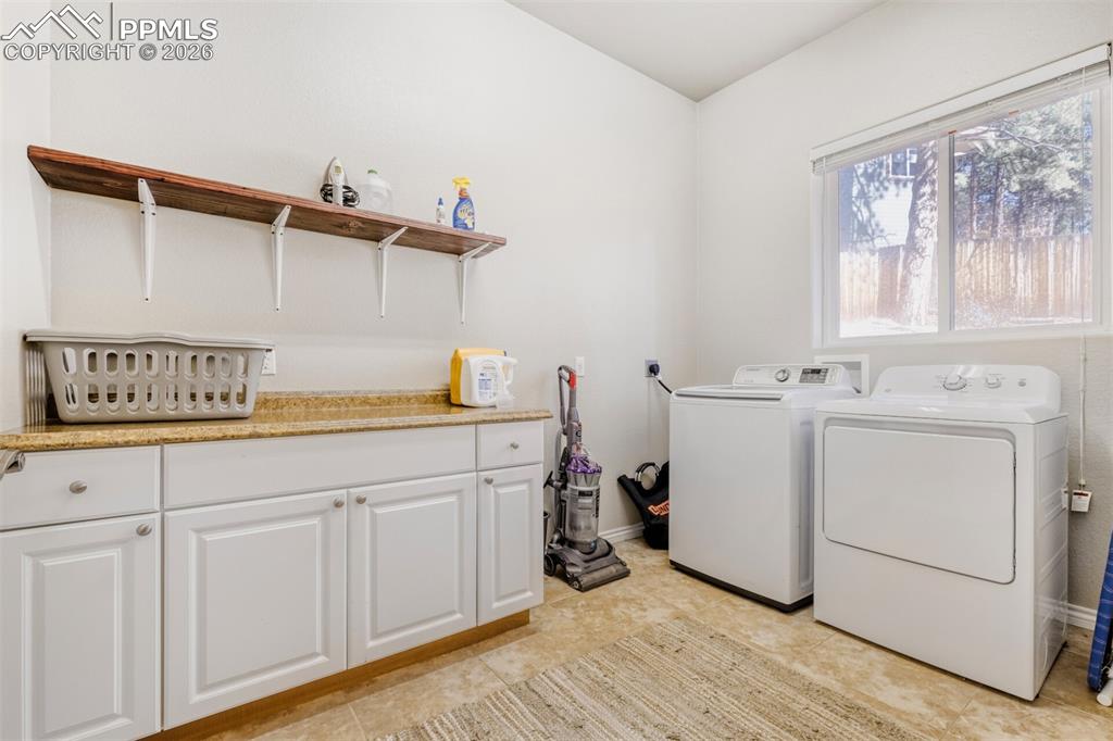 Image 22 of 47: Main Laundry room featuring separate washer and dryer and cabinet space