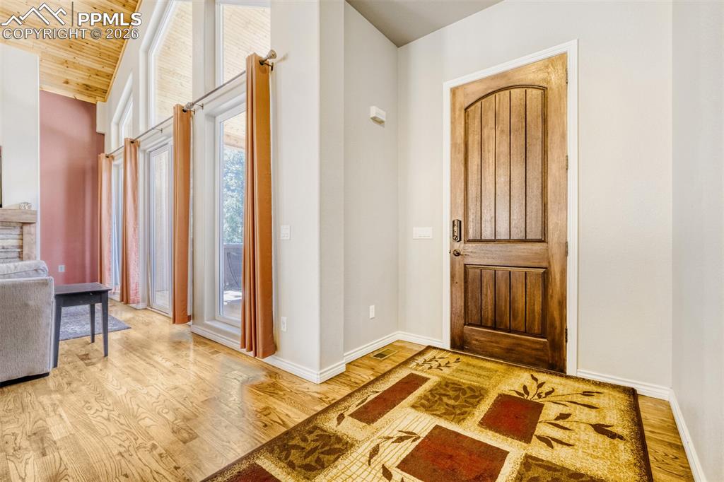 Image 4 of 47: Foyer with hardwood floors and wooden vaulted ceiling