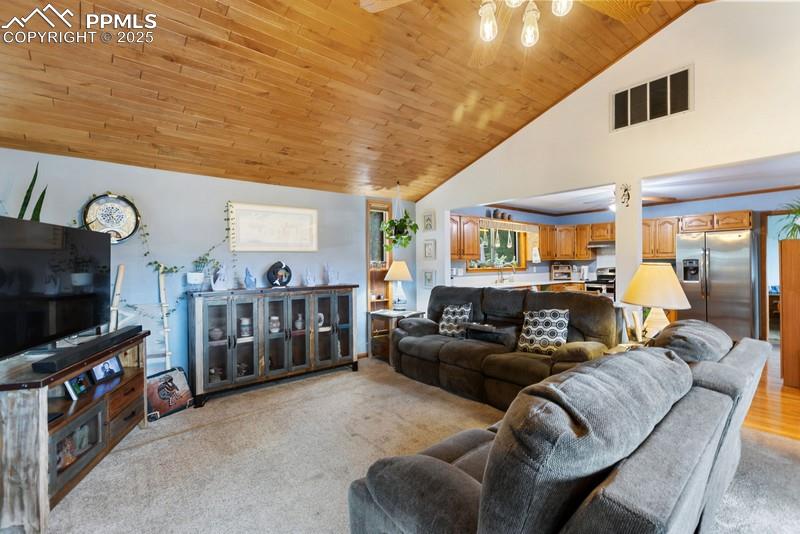Image 15 of 37: Living room featuring wood ceiling, high vaulted ceiling, and light carpet