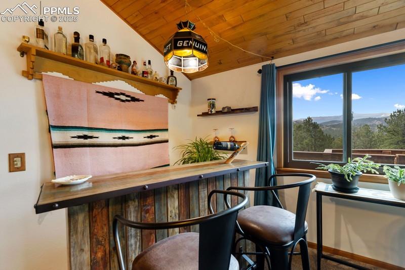 Image 18 of 37: Indoor dry bar featuring a mountain view, wood ceiling, open shelves, and b